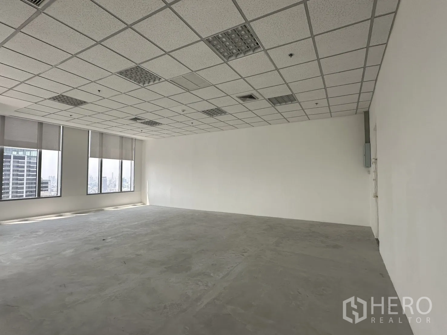 办公室 for rent in Khlong Toei, Bangkok - 开放式办公室，白墙、吊顶灯具与带百叶的大窗户，可见城市景观。