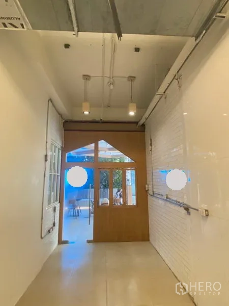 Retail Space for rent in Watthana, Bangkok - Small shop space showing exposed ceiling with track lights and a wood-framed glass door.