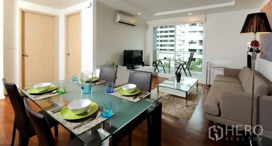 Condominium for rent or sale in Khlong Toei, Bangkok - Open-plan living and dining room with sofa, glass table and balcony city view in a Sukhumvit condominium.
