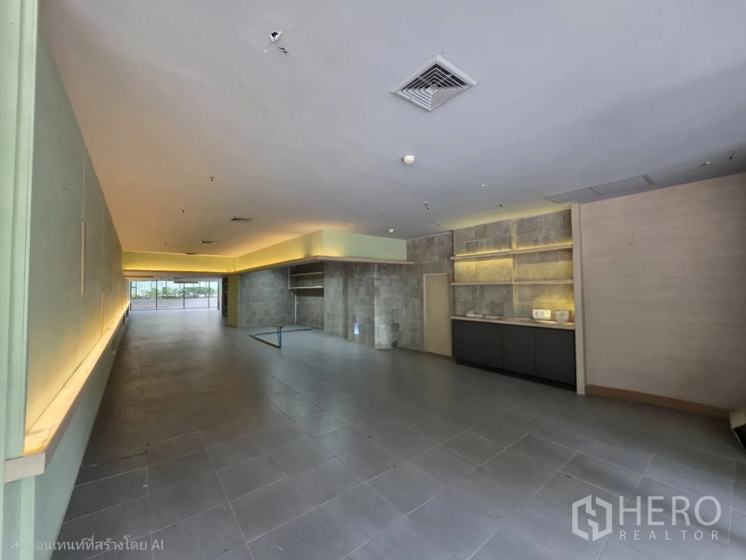 零售空间 for rent in Khlong Toei, Bangkok - 开放式室内空间，灰色地砖与内置层架和柜台。