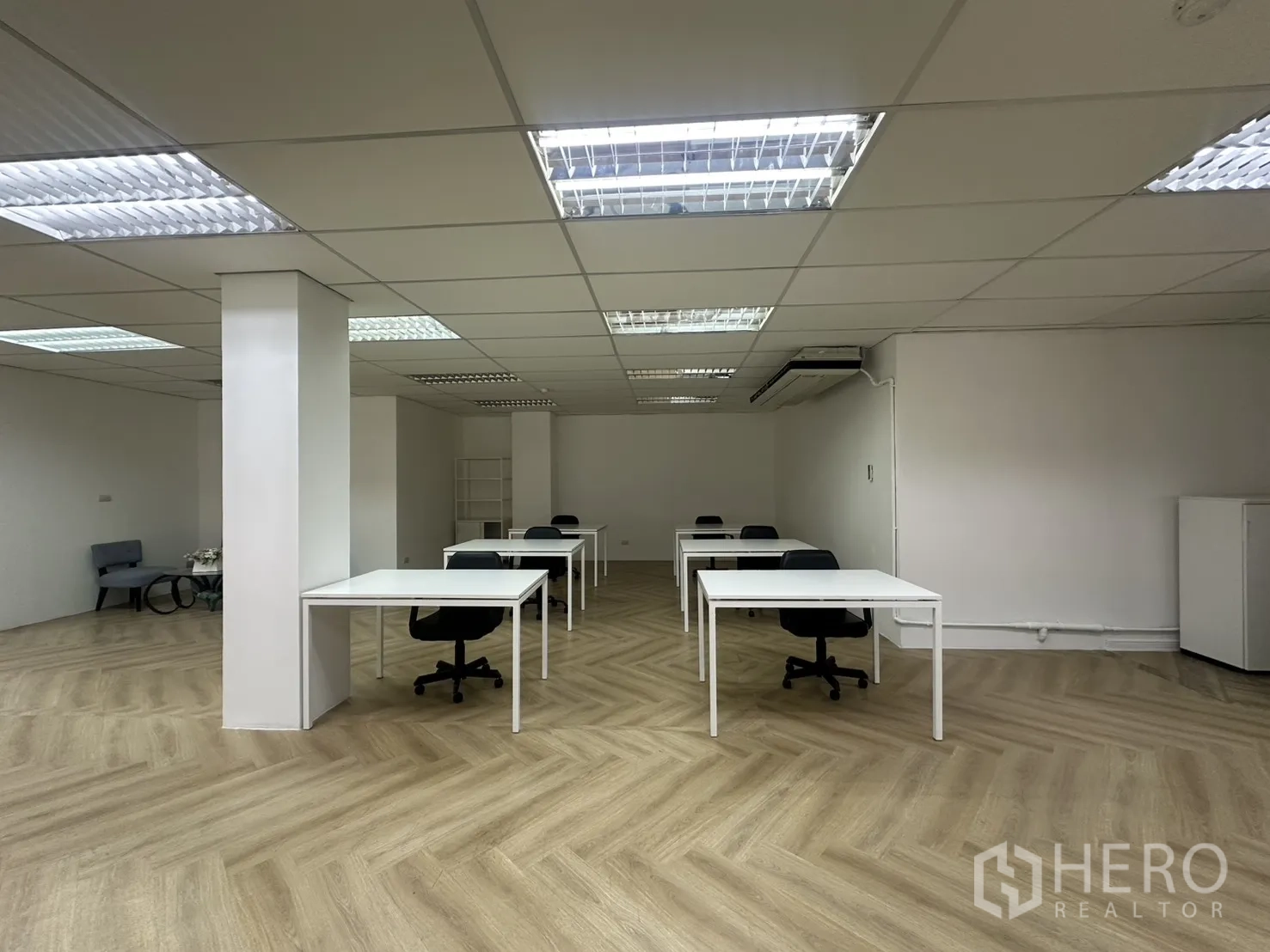 Office Space for rent in Pathum Wan, Bangkok - Open office area with rows of white desks, office chairs, herringbone floor, and a wall-mounted air-conditioning unit.