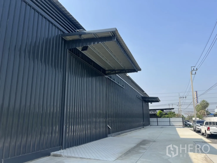 Warehouse for rent in Lat Krabang, Bangkok - Modern metal-clad warehouse exterior with a covered loading bay and wide concrete driveway.
