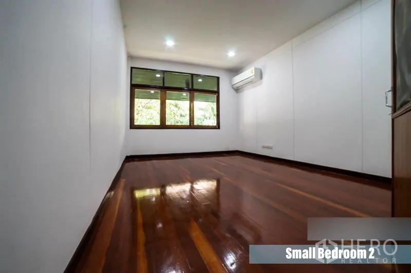 Detached House for rent in Khlong Toei, Bangkok - Cozy bedroom with wooden flooring, window and wall‑mounted air conditioner.