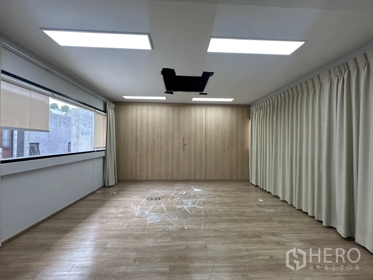 Home Office for rent in Pathum Wan, Bangkok - Multipurpose studio room with curtains, built-in wood cabinet wall and wood floors.