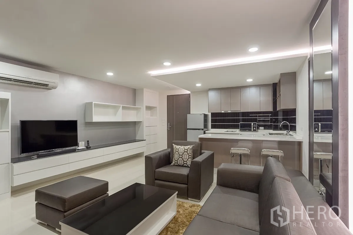 公寓 for rent in Khlong Toei, Bangkok - 开放式客厅配沙发、电视柜与壁柜，并与厨房相连。