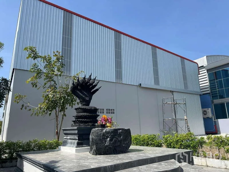 Warehouse for rent in Prawet, Bangkok - Street-side view of metal-clad warehouse facade with landscaped plinth and trees.