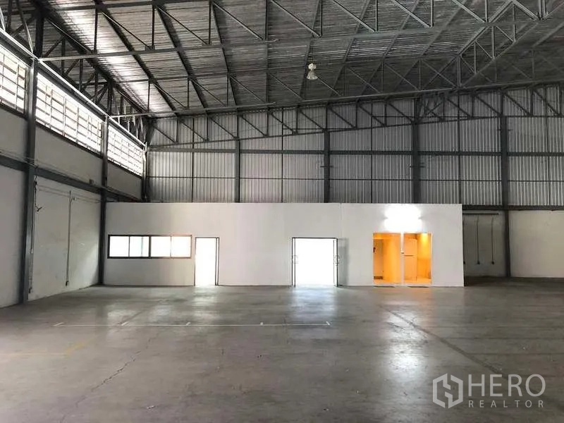 Warehouse for rent in Bang Phli, Samut Prakan - Warehouse interior featuring a partitioned office block and wide clear-span floor under a metal roof.
