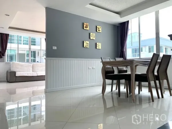 Condominium for rent in Khlong Toei, Bangkok - Bright dining area with gray accent wall, white wainscoting and large windows.