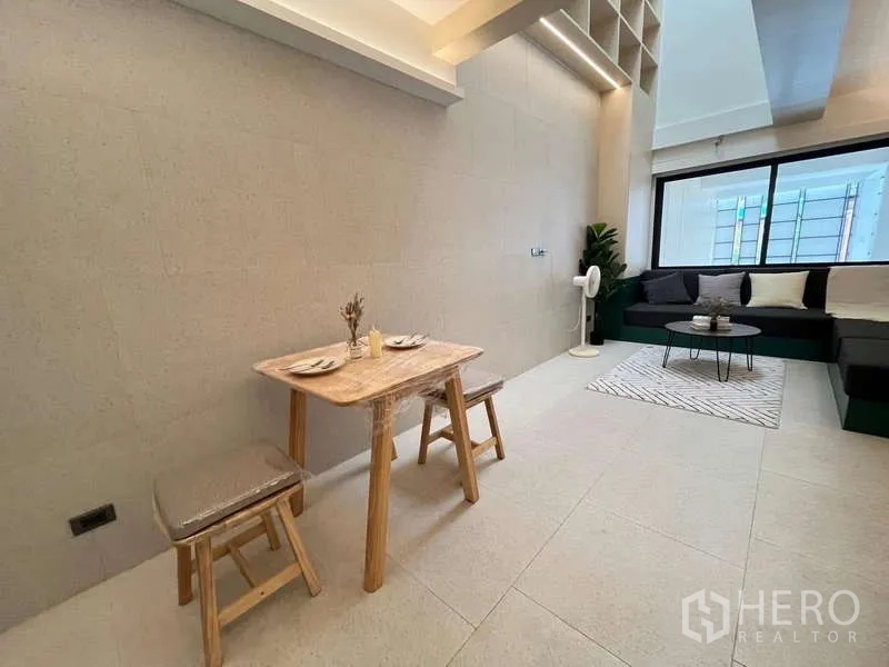 Townhouse for sale in Khlong Toei, Bangkok - Compact dining corner with wooden table and stools beside the lounge.