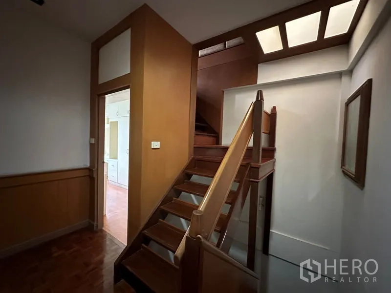 Townhouse for rent in Khlong Toei, Bangkok - Central staircase with skylight and wood finishes connecting the upper floors.