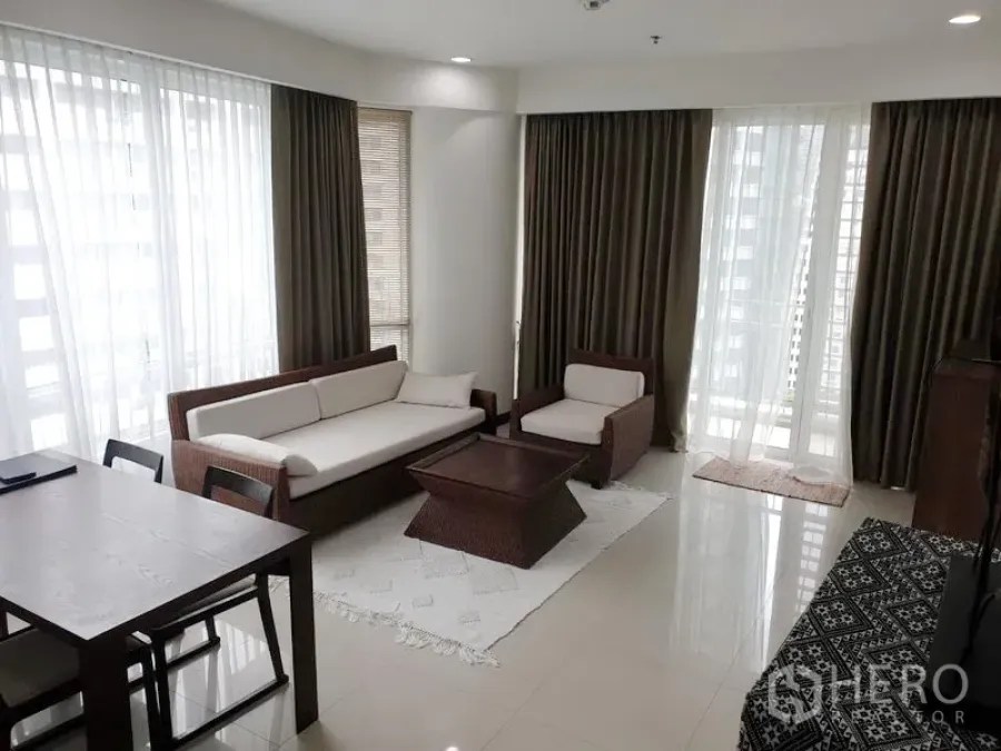 Condominium for rent or sale in Pathum Wan, Bangkok - Bright living room with floor-to-ceiling windows, cream sofa set and access to a balcony in a Bangkok condo.