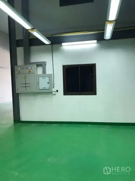 Factory for rent in Bang Phli, Samut Prakan - Production area with green epoxy flooring, window and electrical control panels under strip lighting.