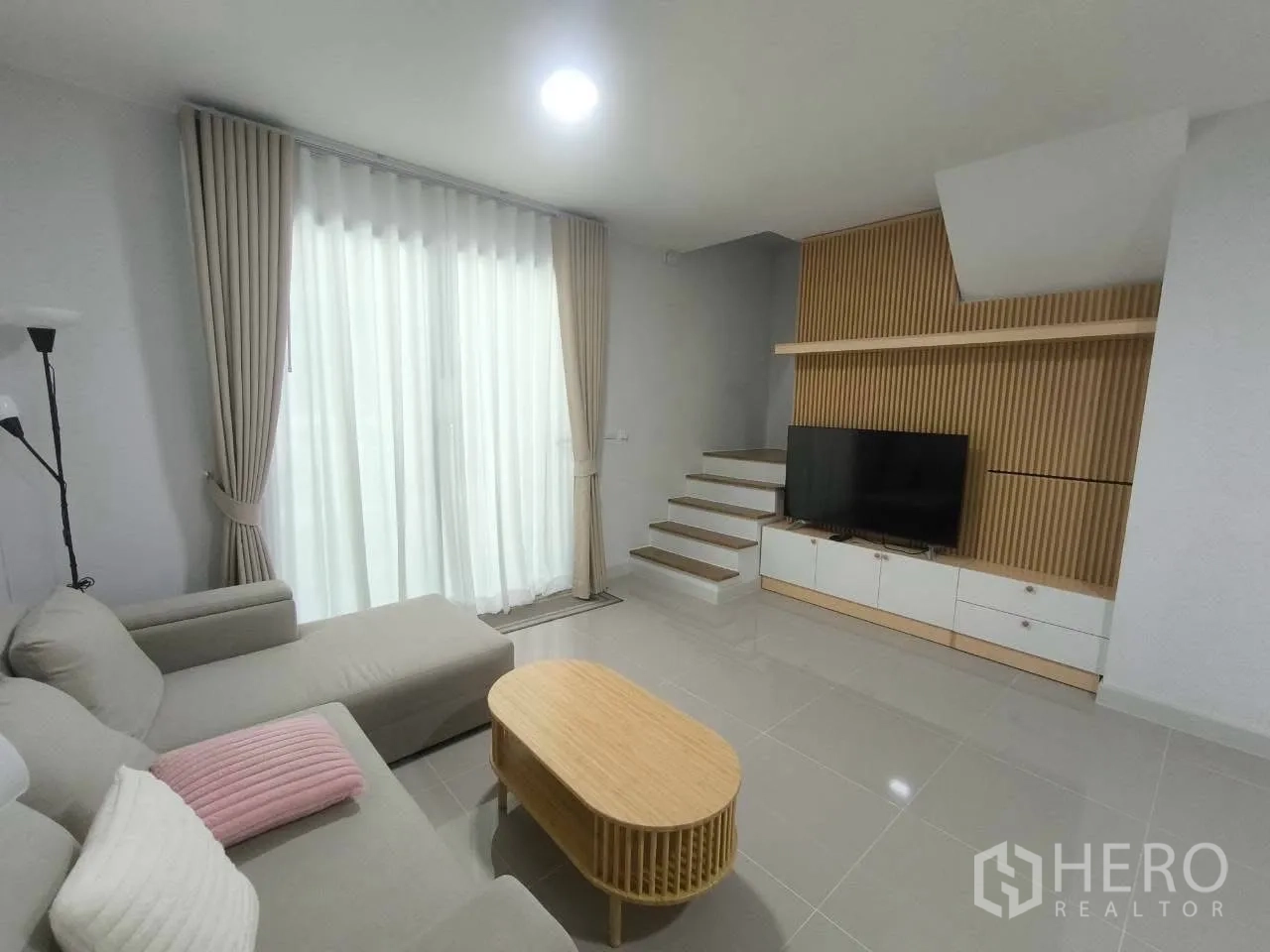 ทาวน์เฮาส์ for rent in Bang Phli, Samut Prakan - ห้องนั่งเล่นสว่าง โซฟาเข้ามุม ผ้าม่านสูงจรดเพดาน และชั้นวางทีวี