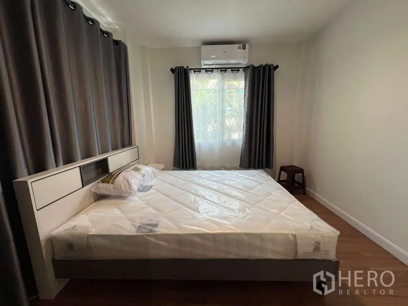 Detached House for rent in Bang Kapi, Bangkok - Cozy bedroom with double bed, dark curtains and wall‑mounted air conditioner.