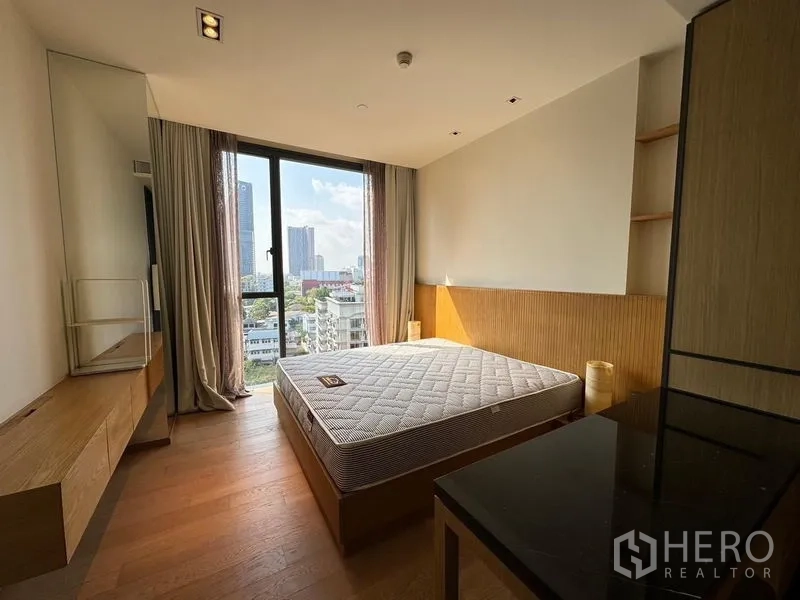 Condominium for rent - Bedroom with large window, bed base and city view over the Sukhumvit area.