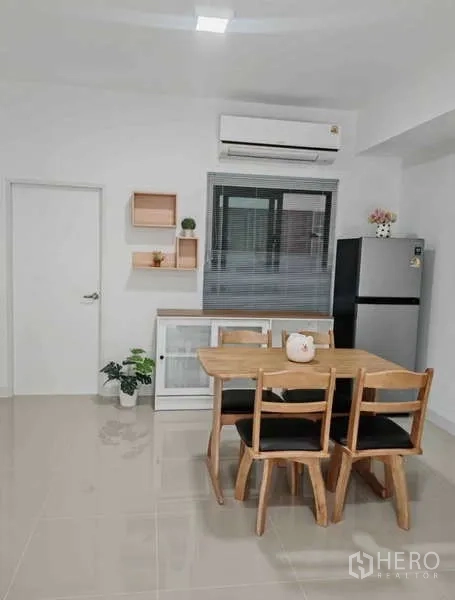 Townhouse for rent in Bang Phli, Samut Prakan - Dining nook with wooden table and four chairs, window blinds, shelves and air conditioning.