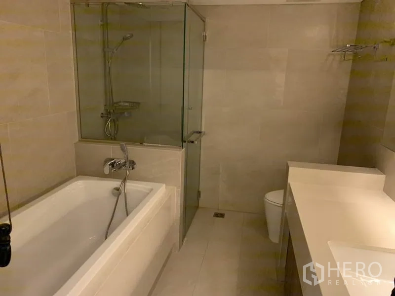 Condominium for rent in Sathon, Bangkok - Modern bathroom with bathtub, glass-enclosed shower and long vanity.