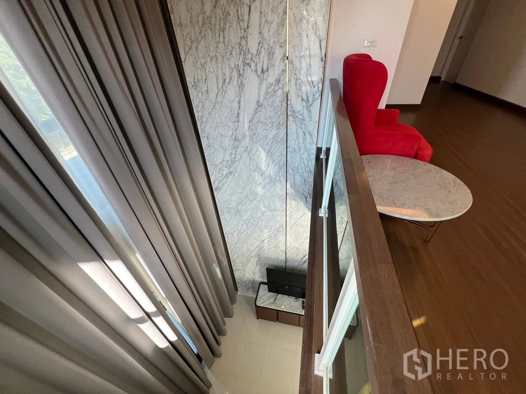 Detached House for rent or sale in Prawet, Bangkok - View from mezzanine with glass railing over double-height living area and marble wall.