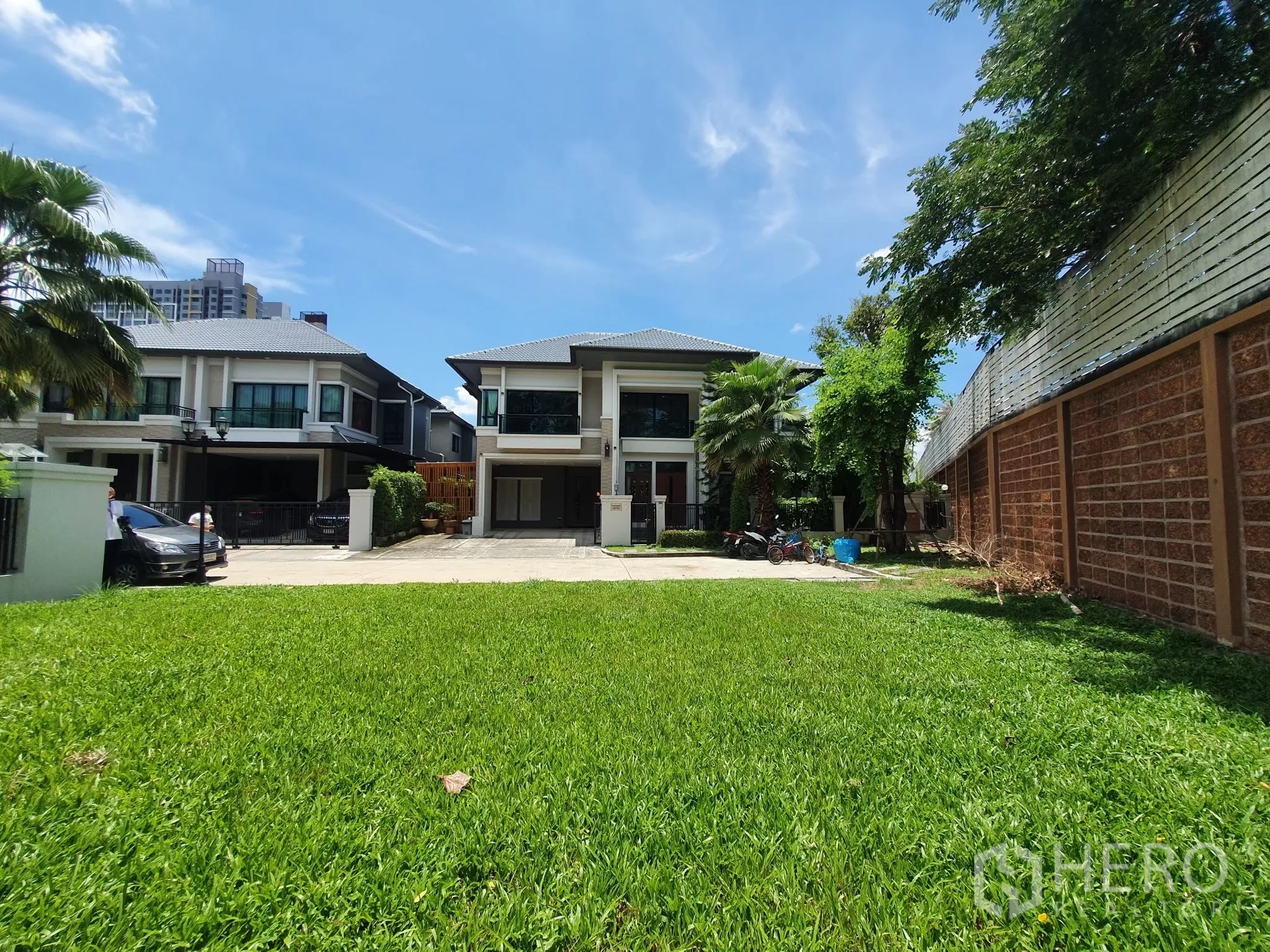 Detached House for rent in Bang Khae, Bangkok - Front lawn looking toward a modern two‑storey house under blue skies.