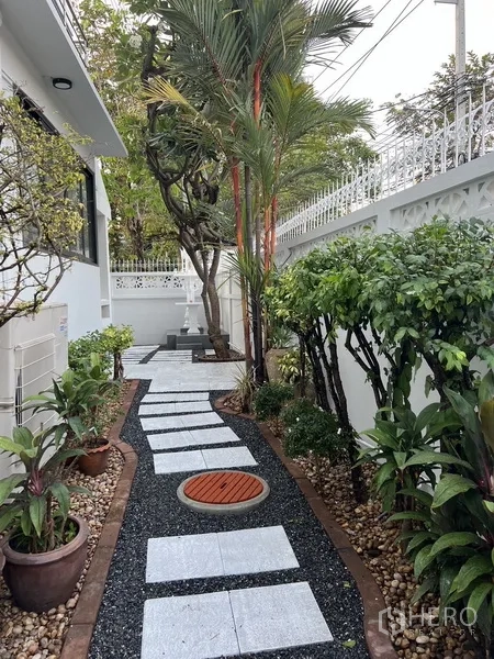 Detached House for rent in Bang Rak, Bangkok - Landscaped side garden featuring a stone pathway, tropical plants, and a privacy wall.