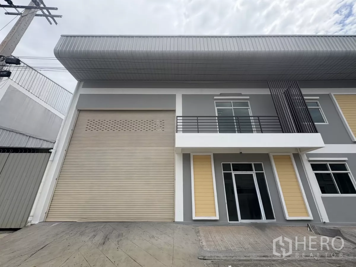 Factory for rent in Phra Samut Chedi, Samut Prakan - Closer view of the warehouse entrance showing the large roller door and glass-front office.
