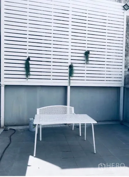 Townhouse for rent in Watthana, Bangkok - Private outdoor terrace with white privacy screen and seating.