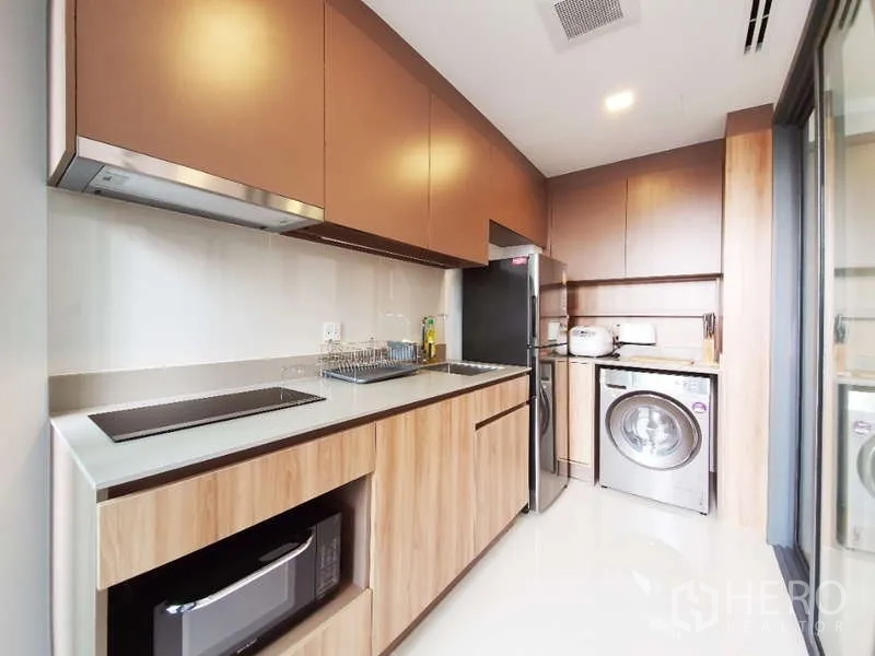 Condominium for sale in Watthana, Bangkok - Modern separate kitchen with built-in cabinets, hob, fridge, microwave and washing machine.