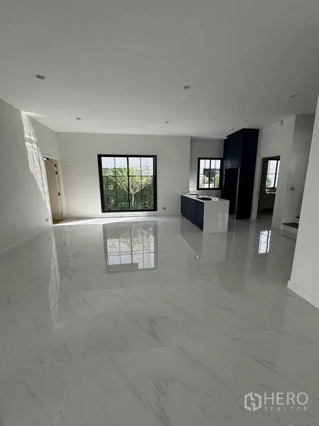 独立式住宅 出租在Bang Khen, Bangkok - 采光充足的开放式客餐厅，亮面大理石纹地砖与大窗户，配备中岛厨房。