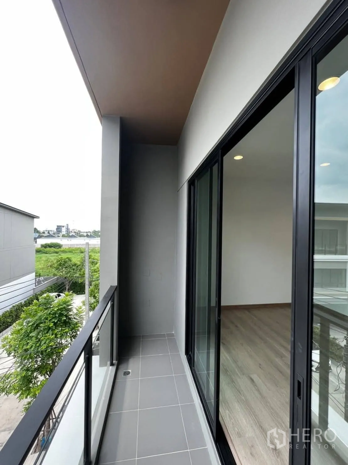 Townhouse for rent in Bang Khen, Bangkok - Narrow balcony with tiled floor and black railing accessed via sliding doors.
