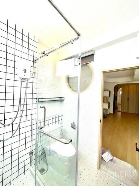 Townhouse for rent in Khlong Toei, Bangkok - Bright bathroom with glass shower enclosure and grid tiles.