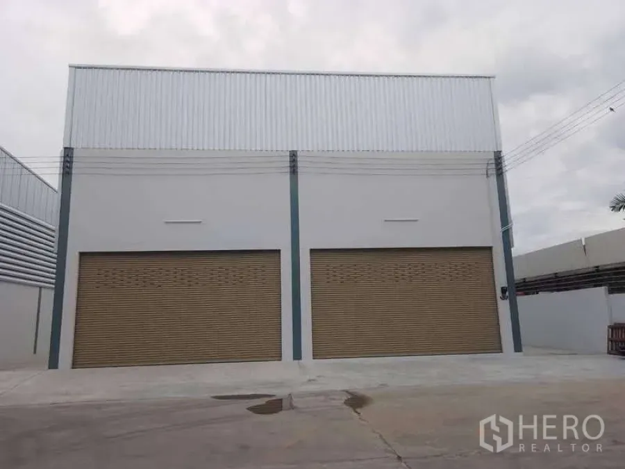 Warehouse for rent in Khlong Toei, Bangkok - Facade with two large brown roller shutters and a wide forecourt.