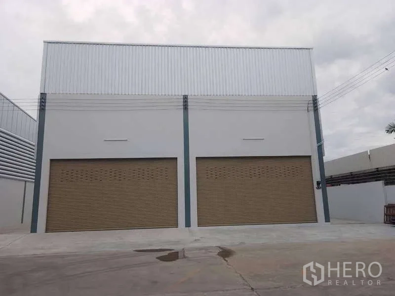 Warehouse for rent in Khlong Toei, Bangkok - Facade with two large brown roller shutters and a wide forecourt.