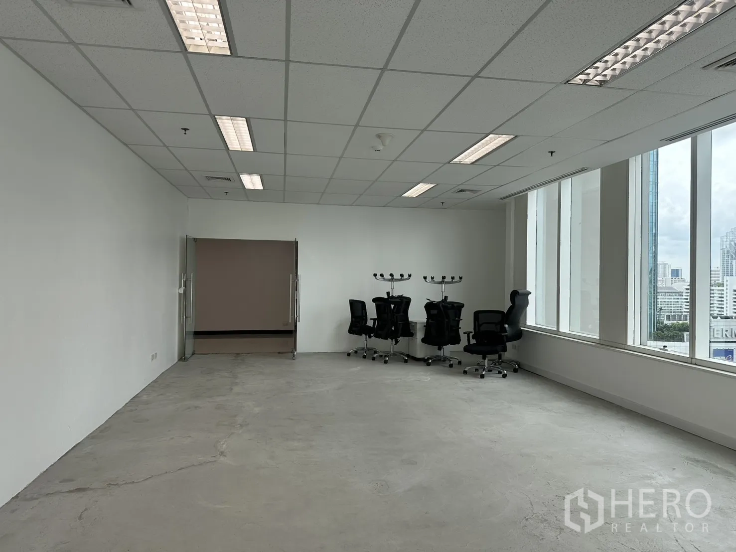 Office Space for rent in Watthana, Bangkok - Open office with glass double doors, rolling chairs, and natural light from corner windows.
