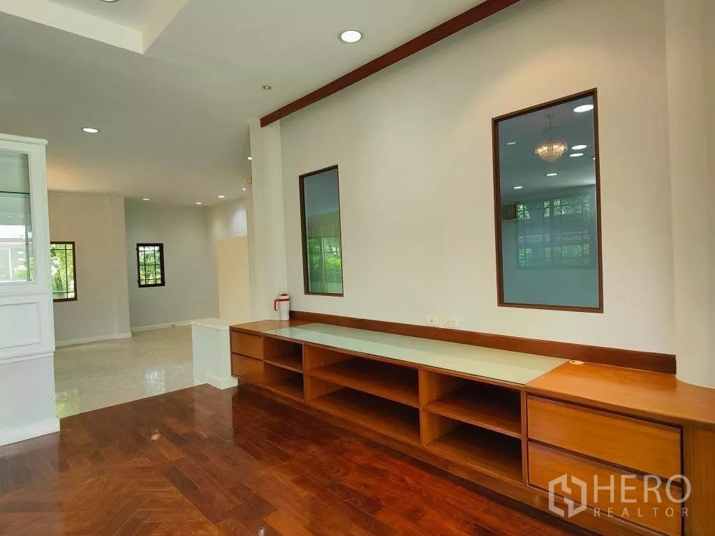 Detached House for rent or sale in Mueang Nonthaburi, Nonthaburi - Lounge with polished wood floor and long built-in TV console with accent windows.