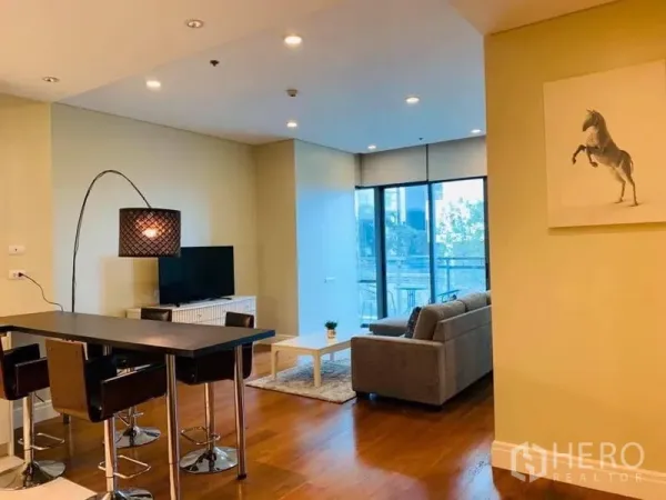 Condominium for rent in Khlong Toei, Bangkok - Open-plan living and dining area with floor-to-ceiling windows and warm wooden floors.