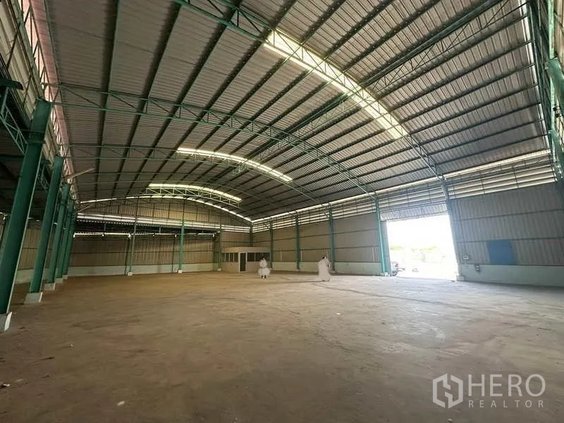 Warehouse for rent in Phra Nakhon Si Ayutthaya - Spacious warehouse interior with high curved steel roof, green columns, and a wide loading entrance.