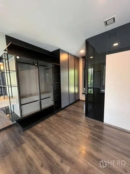 Detached House for rent or sale in Bang Phli, Samut Prakan - Built‑in wardrobe area with glossy black cabinetry and mirrored panels.