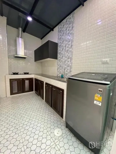 Townhouse for rent in Bang Phli, Samut Prakan - Modern kitchen with white subway tiles, hexagon floor, gas hob, stainless hood and washing machine.