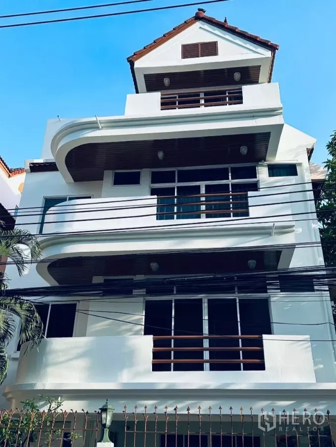 独立式住宅 出租 - 曼谷瓦他那区多层独栋住宅外立面，弧形阳台与红瓦屋顶。