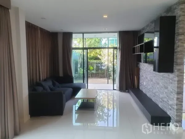 Detached House for sale in Bang Kapi, Bangkok - Open-plan lounge with floor-to-ceiling sliding doors to the garden and glossy white tiles.
