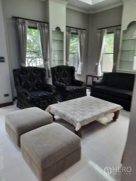 Detached House for rent in Khlong Toei, Bangkok - Second sitting area with armchairs, coffee table and corner windows.
