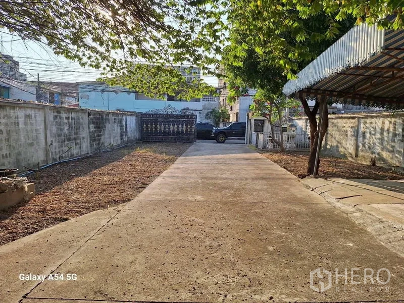 Detached House for rent in Bang Na, Bangkok - Wide concrete driveway with shaded carport awning and ample parking space.