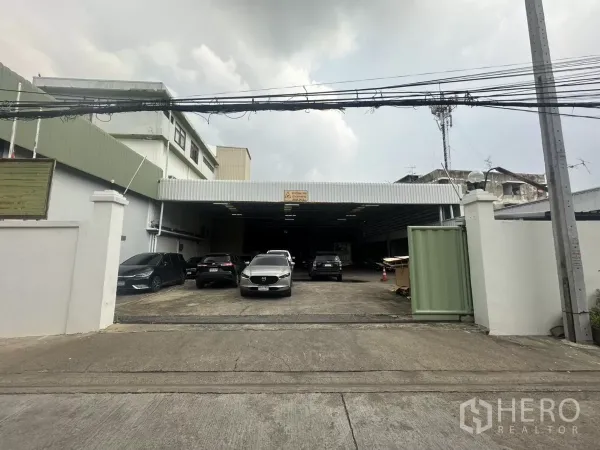 Warehouse for rent in Yan Nawa, Bangkok - Front entrance driveway leading to a covered loading bay of the warehouse with several parked cars.