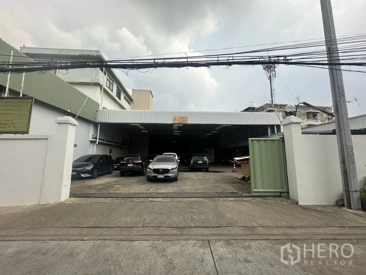 Warehouse for rent in Yan Nawa, Bangkok - Front entrance driveway leading to a covered loading bay of the warehouse with several parked cars.