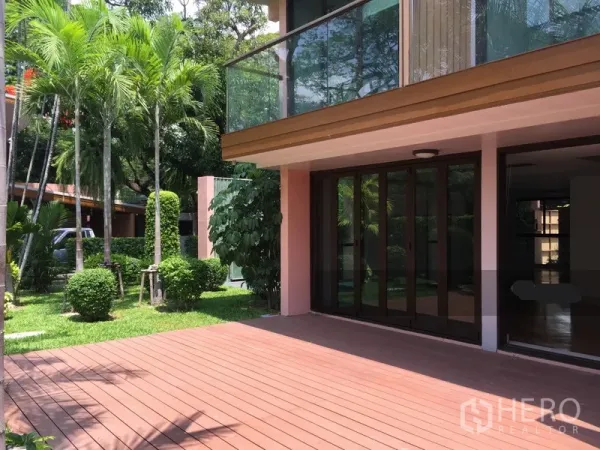 Detached House for rent in Sathon, Bangkok - Timber deck with sliding glass doors and an upper balcony facing a lush garden