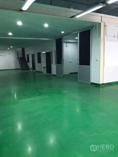 Factory for rent in Bang Phli, Samut Prakan - Wide production space with multiple sliding doors and a staircase to the upper level.