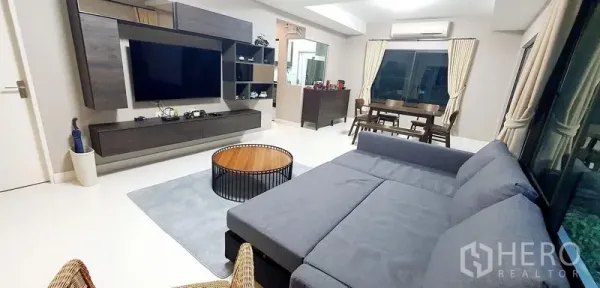 Detached House for rent in Bang Phli, Samut Prakan - Open-plan living and dining room with sectional sofa, TV and sliding glass doors