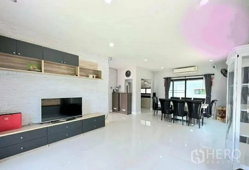 Detached House for sale in Pathum Thani - Spacious open-plan living and dining area with built-in TV wall and glossy tile floors.