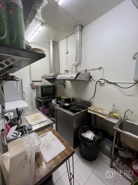 Retail Space for rent in Watthana, Bangkok - Compact commercial kitchen with range hood, prep counters, sink and storage shelves.