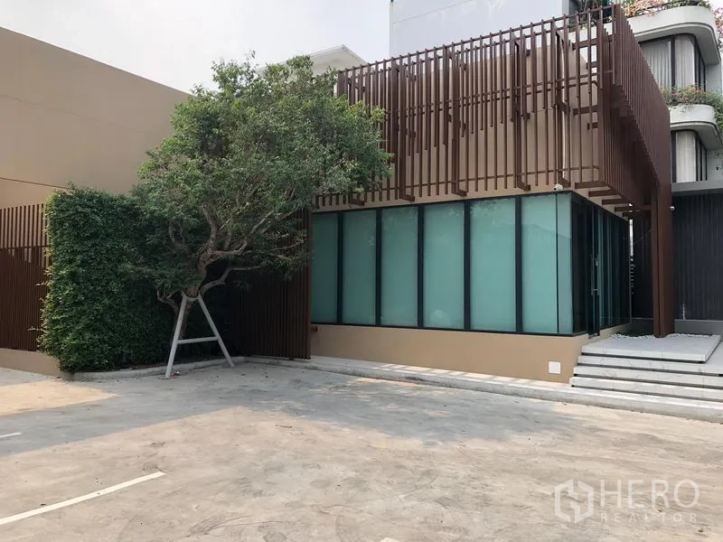 Retail Space for rent in Watthana, Bangkok - Modern low-rise retail building with frosted glass facade, vertical slatted screens and a large forecourt parking area in Watthana, Bangkok.